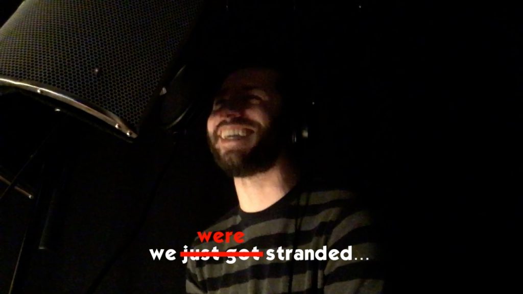 A still frame from a video where Bryce Kalal is smiling next to a microphone inside a vocal recording booth. Overalyed on the bottom of the image is white text that reads: "we just got stranded...," but "just got" is crossed out with a red line and replaced with "were."